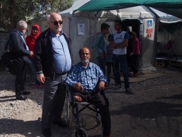 Ο Ιωάννης Βαρδακαστάνης με έναν πρόσφυγα σε αναπηρικό καρότσι